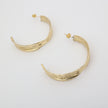 Pair of polished gold leaf-shaped bronze hoop earrings.