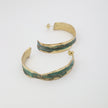Pair of textured bronze hoop earrings with a green patina finish.