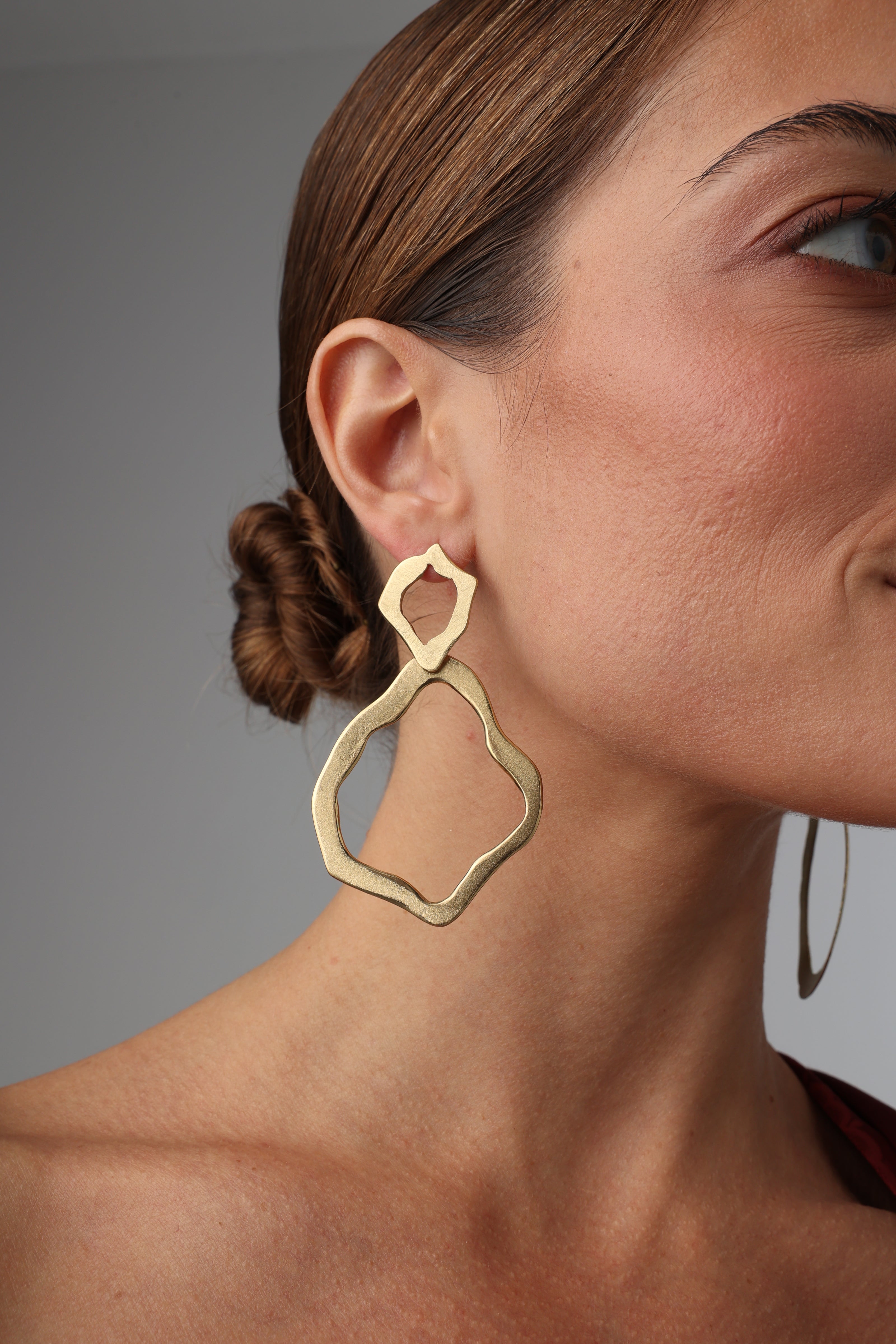 Pair of handmade brushed bronze earrings with abstract organic shapes on a white background.