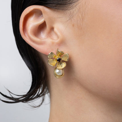 Handmade brass flower stud earring with amethyst crystal and pearl drop, worn on ear