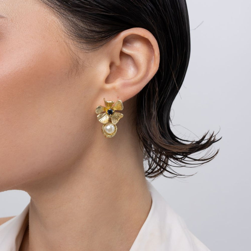 Brass flower stud earring with sapphire crystal and pearl drop, worn on ear