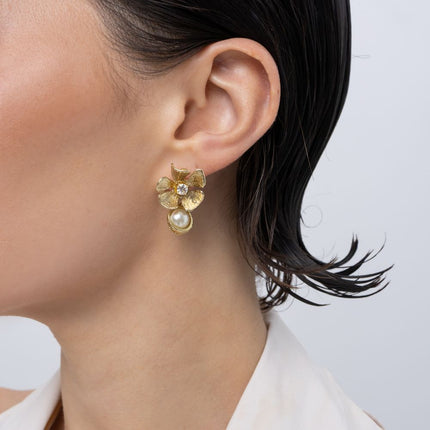 Brass flower stud earring with clear crystal and pearl drop, worn on ear