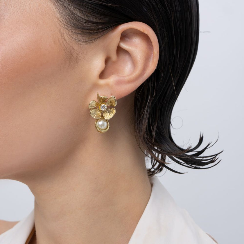 Brass flower stud earring with clear crystal and pearl drop, worn on ear