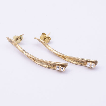 Glade Earrings flat lay, handmade brass linear earrings with elongated organic silhouette and crystal accent
