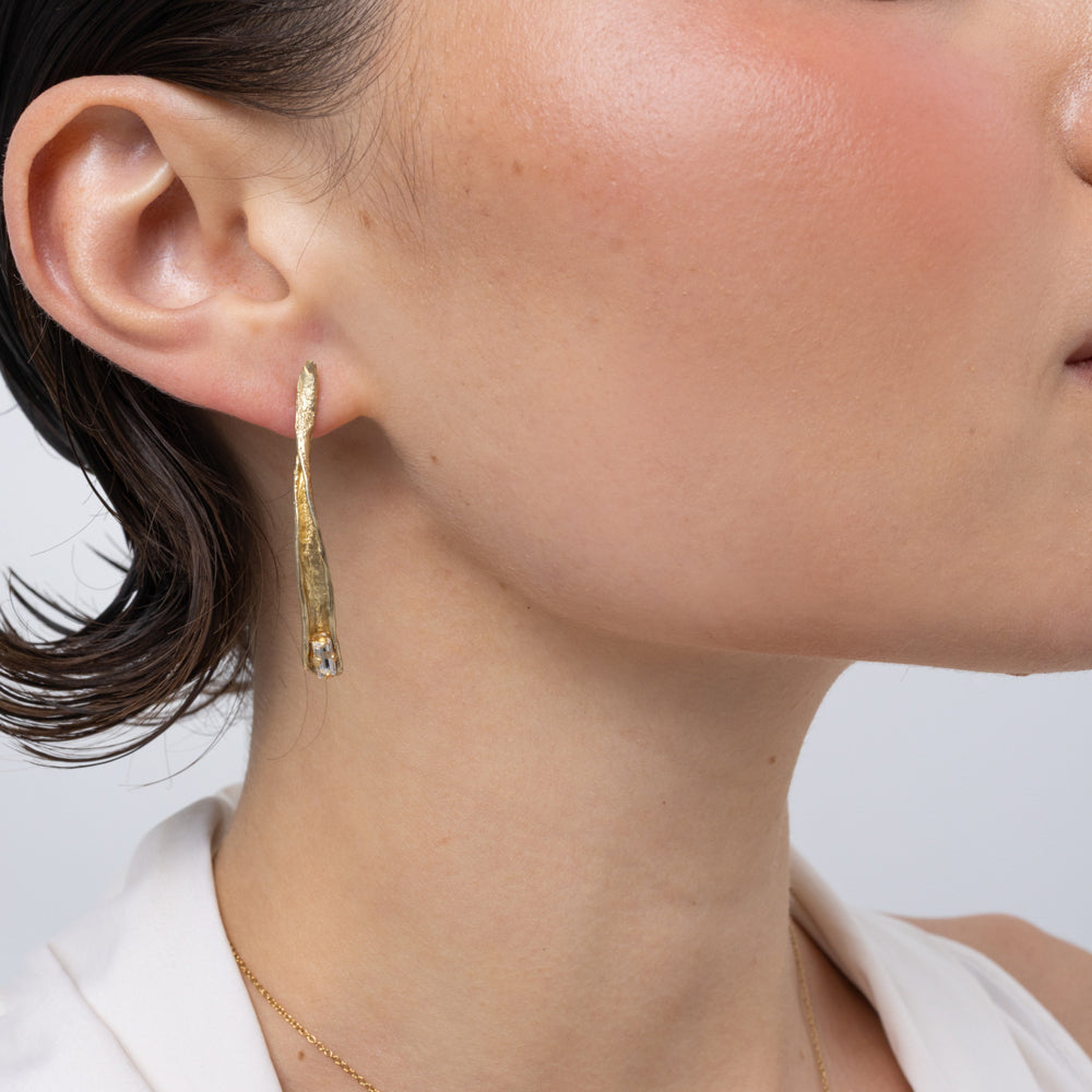 Glade Earrings close-up, handmade brass earrings with organic bark-like texture and tiny crystal at the tip