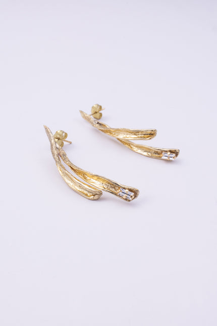 Pixie Earrings flat lay, handmade brass linear earrings with elongated split silhouette and crystal accent