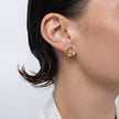 Brass flower stud earring with clear crystal center, worn on ear