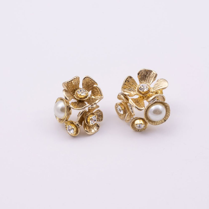 A pair of gold-toned flower-shaped stud earrings with white pearl accents and small clear rhinestones, displayed on a clean white background.