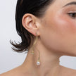 Brass winding stem earring with two pearl drops worn on ear, close-up, Tangled