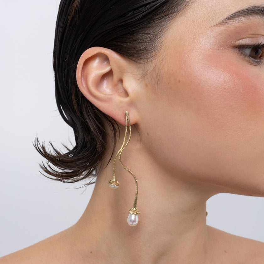 Brass winding stem earring with two pearl drops worn on ear, close-up, Tangled
