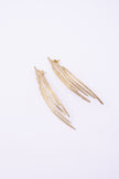 Pine Earrings flat lay, handmade brass linear earrings with elongated peacock feather silhouette