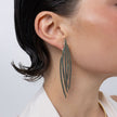 Pine Earrings on model, handmade brass long feather earrings worn on ear showing length and movement