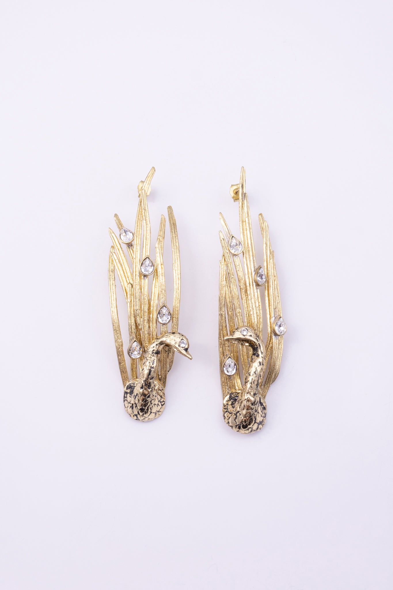 Peacock Earrings close up, handmade brass earrings with faceted teardrop crystals set into patinated feather blades
