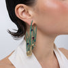 Peacock Earrings on model, handmade brass long drop earrings with sculpted bird and feather blades worn on ear showing length and movement