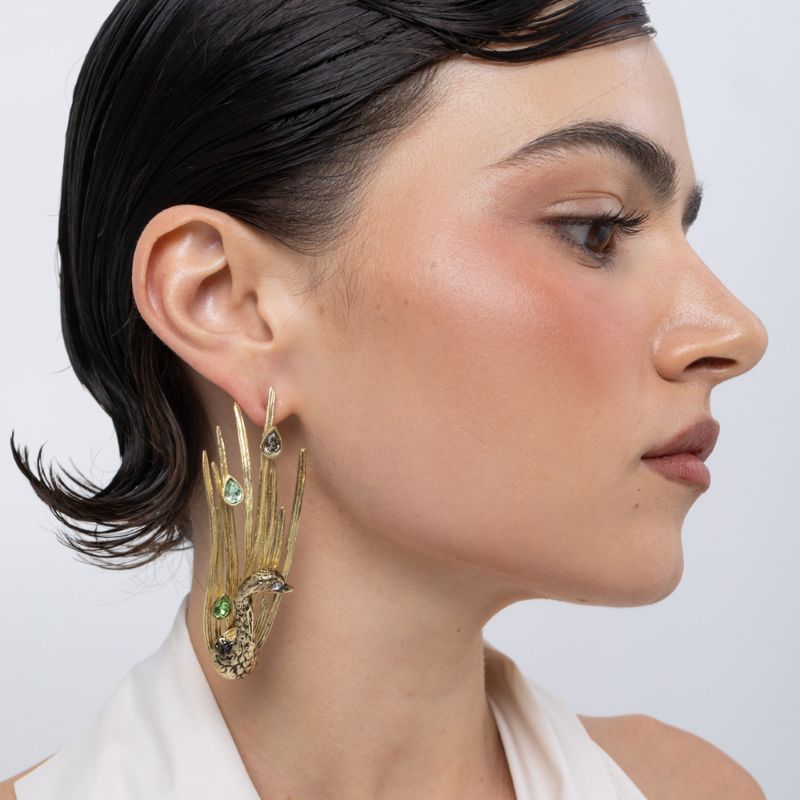 Peacock Earrings on model side view, handmade brass statement earrings with textured peacock body and teardrop crystals framing the jawline
