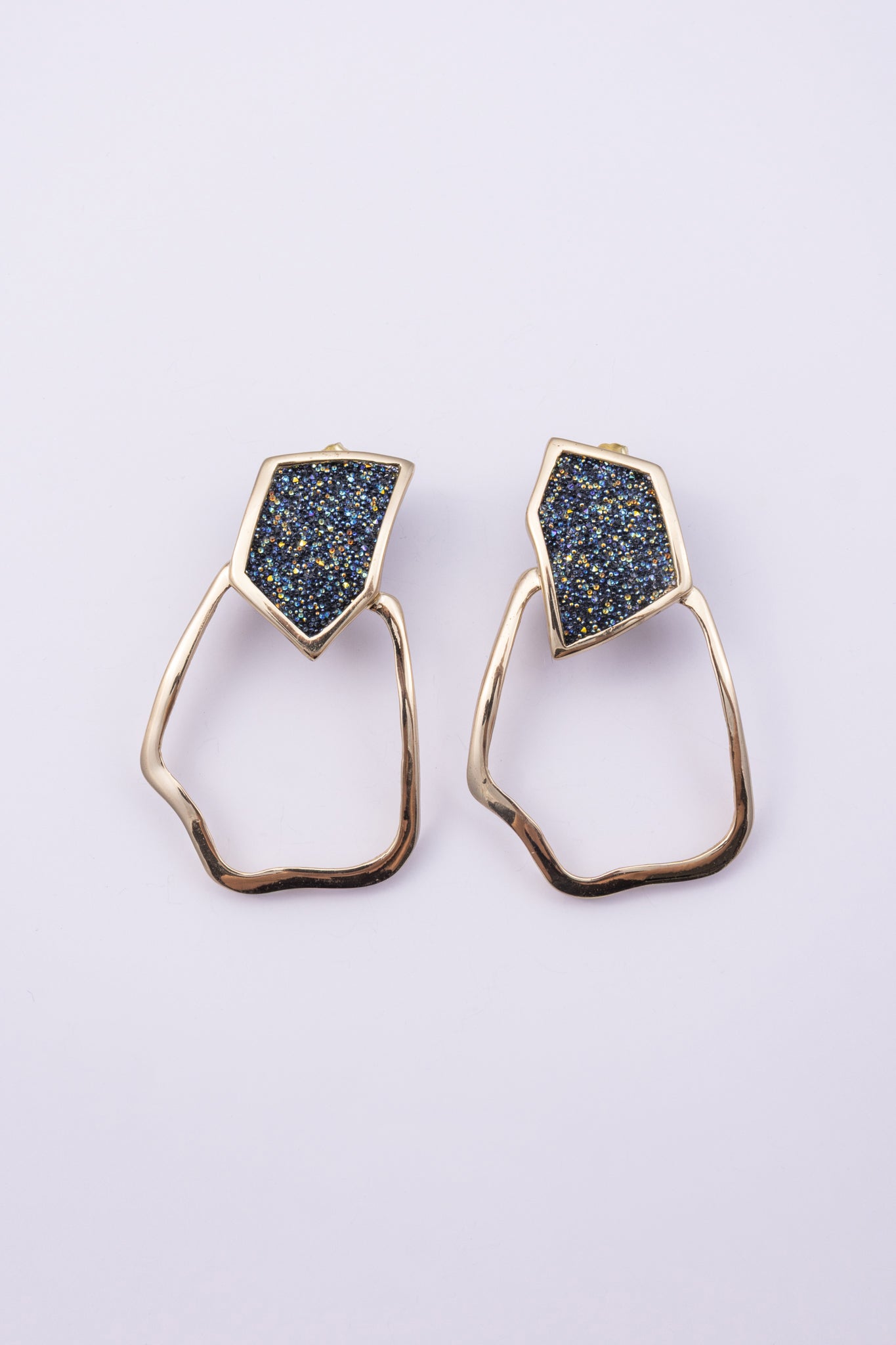 Glow Earrings on white background: handmade brass statement earrings with crystal shard and open organic drop