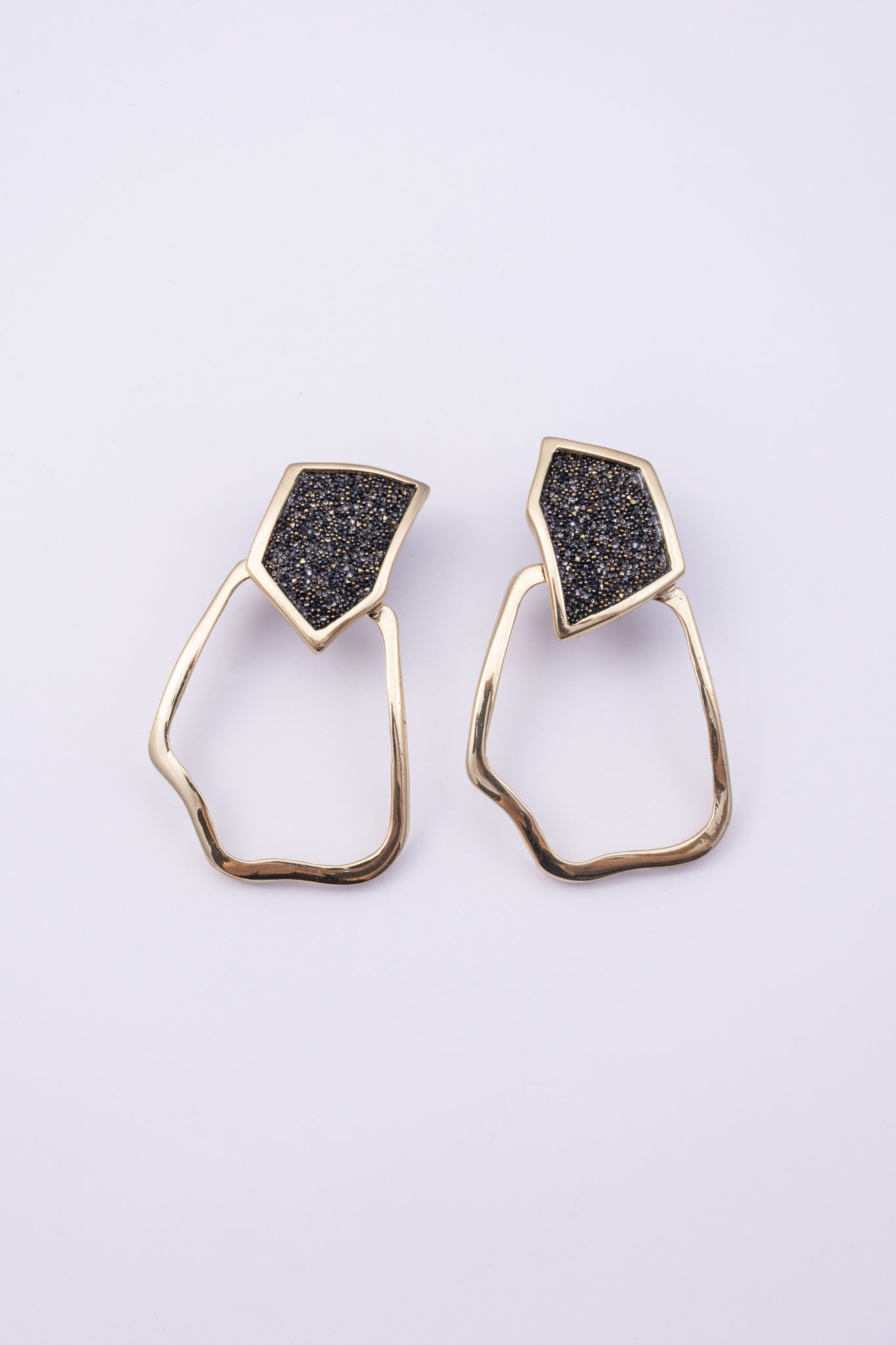 Glow Earrings front view: handmade brass geometric earrings with faceted crystal stud and irregular loop