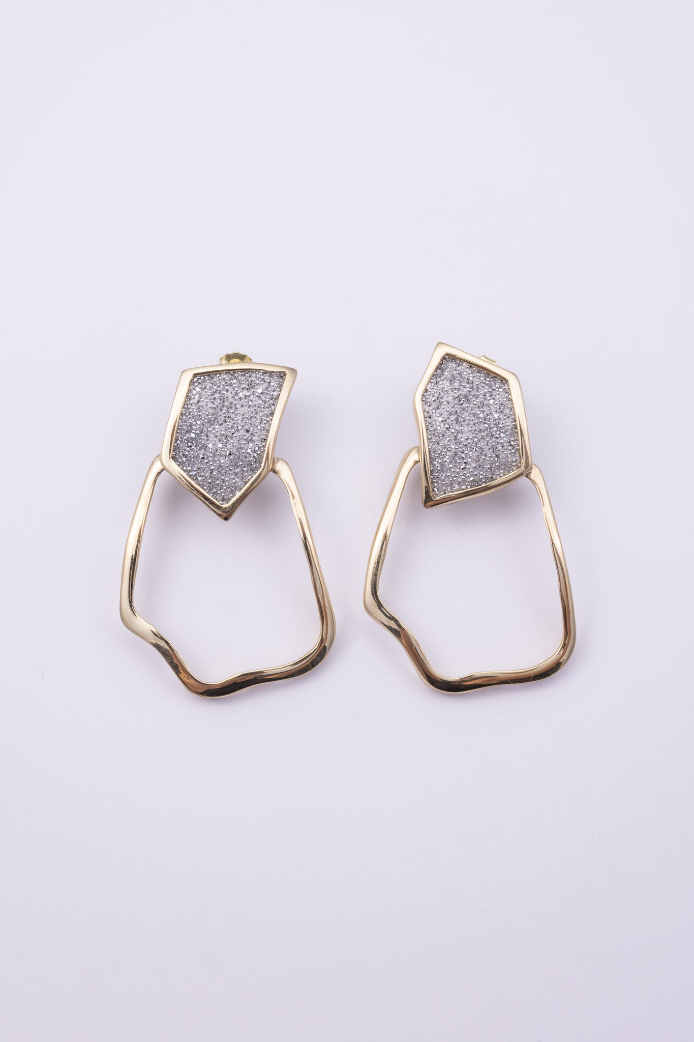 Glow Earrings close up: handmade brass earrings with tiny faceted crystals set in a sleek brass frame