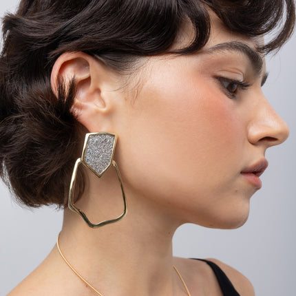 Glow Earrings on model: handmade brass sculptural earrings with angular crystal top and flowing frame