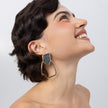 Glow Earrings on model, side view: handmade brass drop earrings with open organic loop and crystal shard