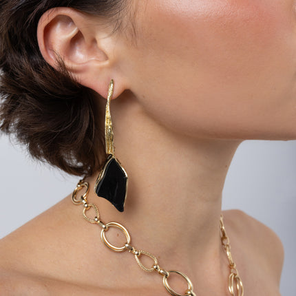 Kite Earrings on model side view, handmade brass statement earrings with twisting stem and kite shaped resin stone
