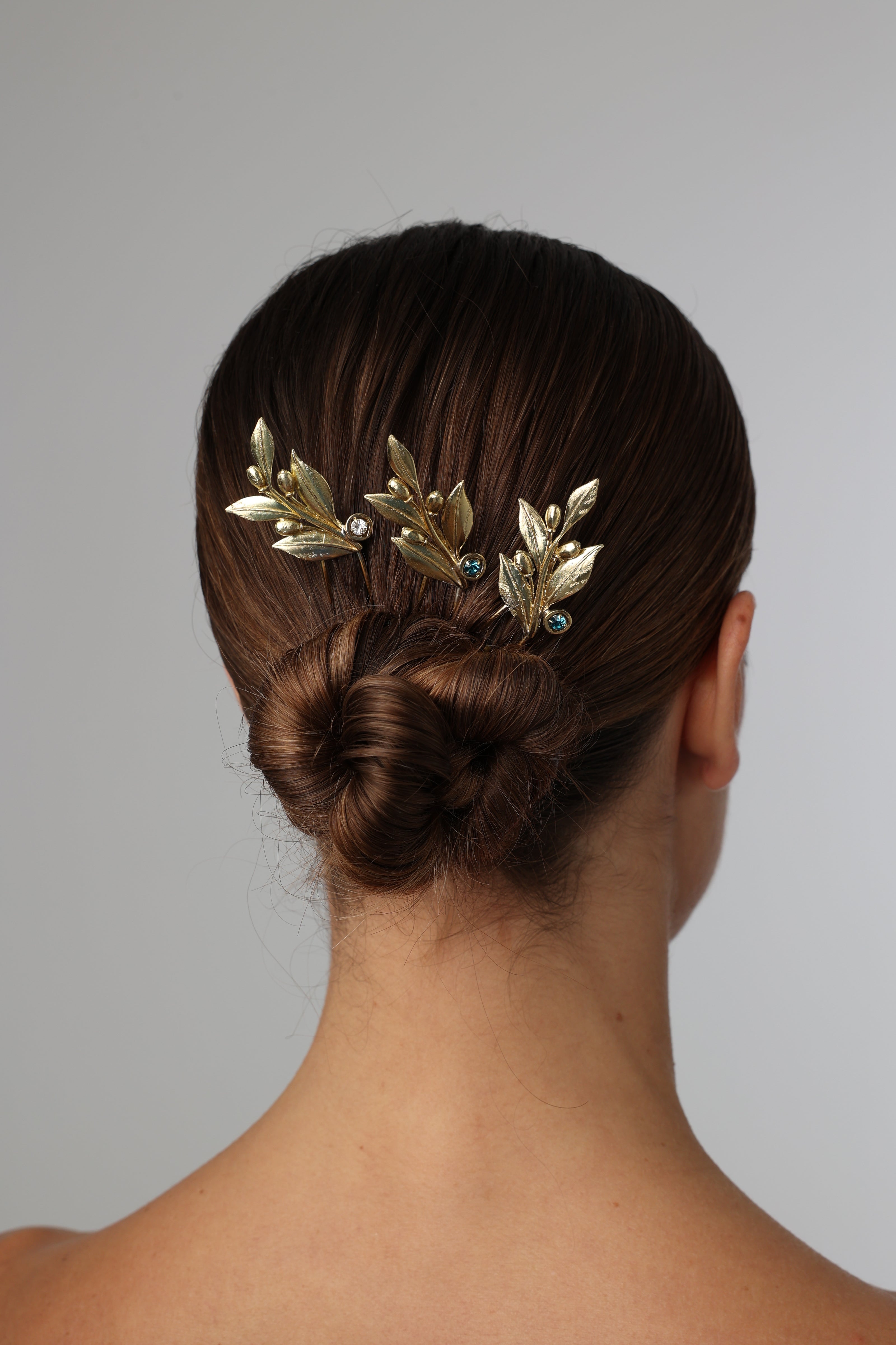 Model wearing a handcrafted gold-plated olive leaf hair pin with crystal accents.