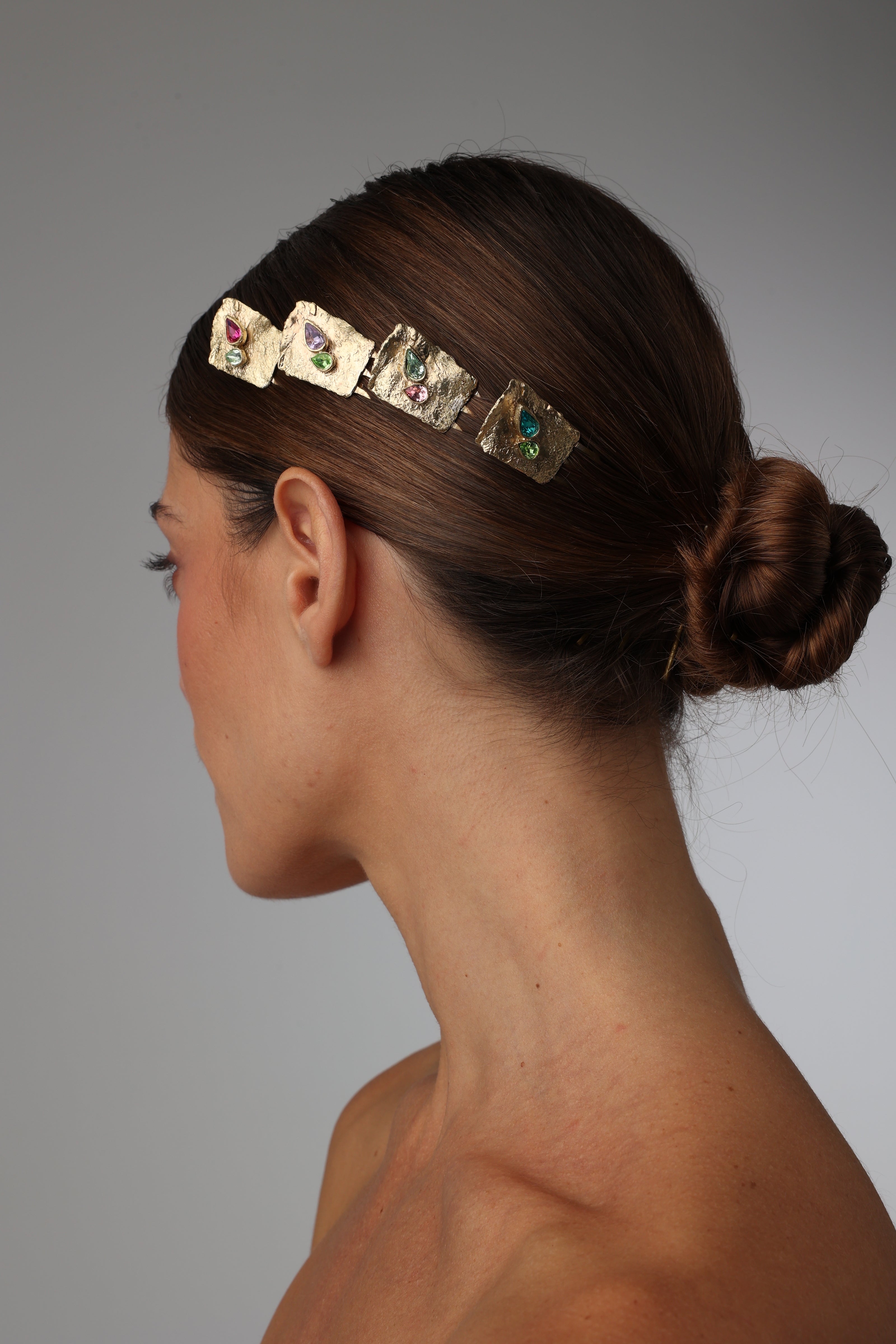 Model wearing a handcrafted gold-plated hair accessory with natural gemstones and organic texture.
