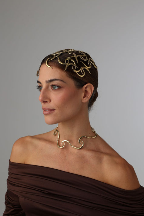 handmade brass sculptural wave headpiece with open lattice curl design on model, side view