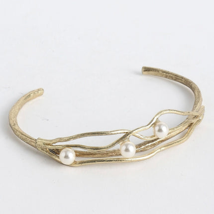 Gold bracelet with pearls on a light gray background